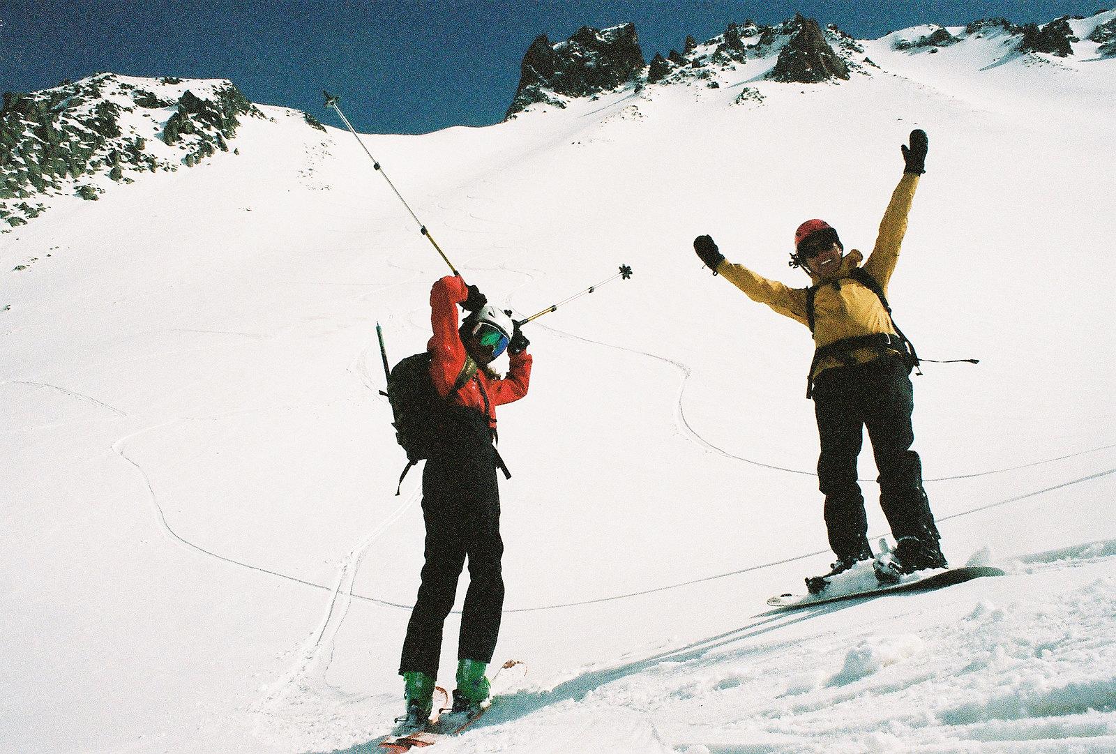 Two backcountry skiers having fun on a Gudauri ski tour, one holding their poles up like antennae.
