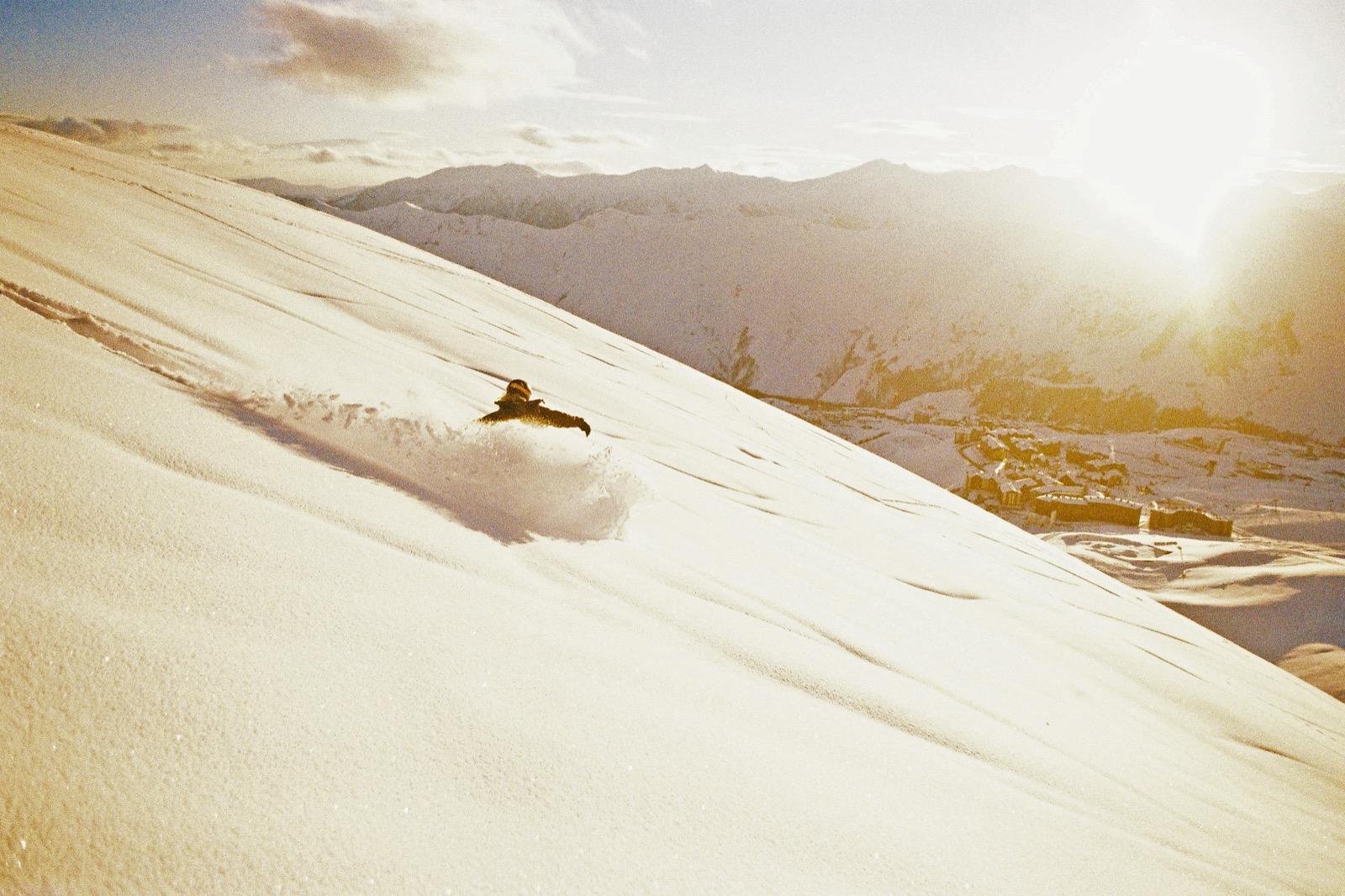 Snowboarder slashing powder at sunset above Gudauri.