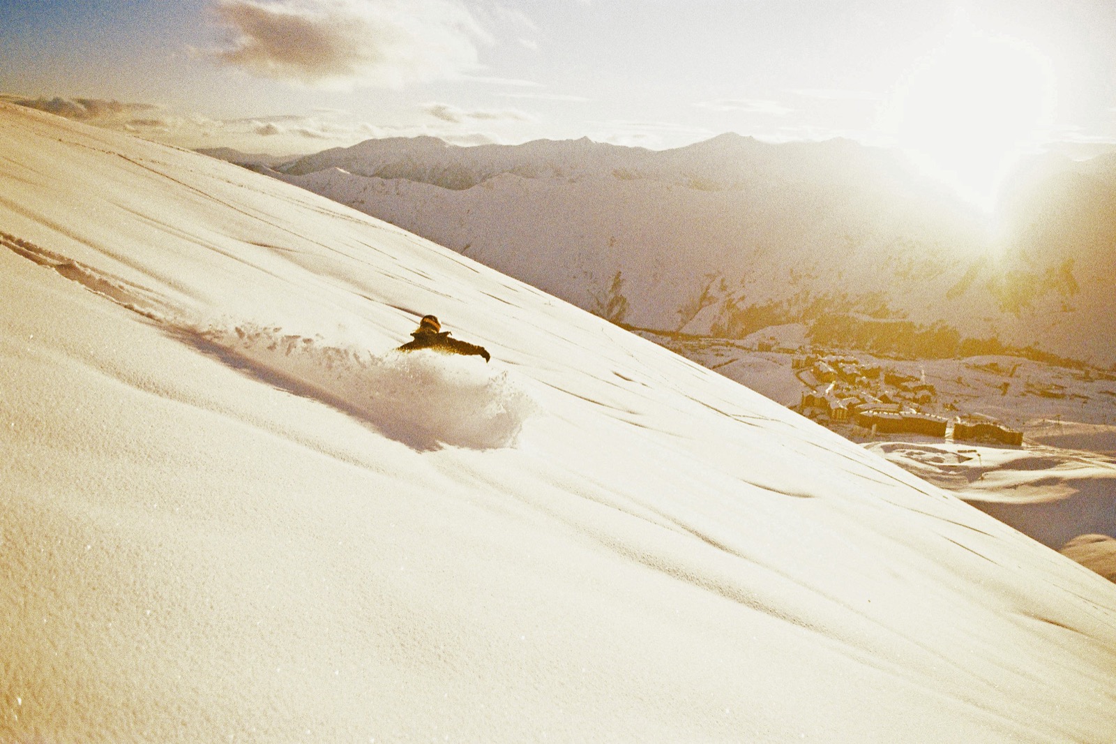 Snowboarder slashing powder at sunset above Gudauri.